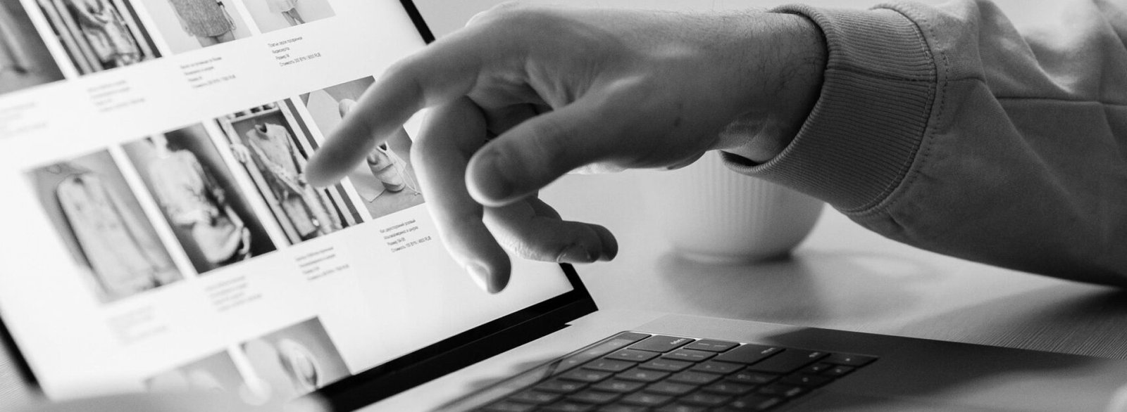 Black and white photo of a person shopping online on a laptop, highlighting e-commerce technology.